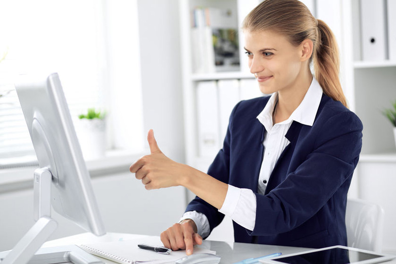 woman at computer desk thumbs up