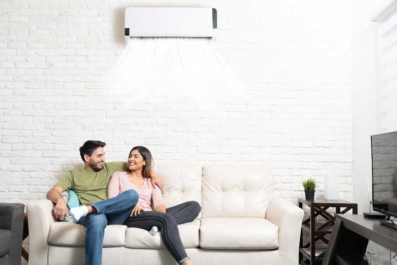 couple on couch enjoying heat pump